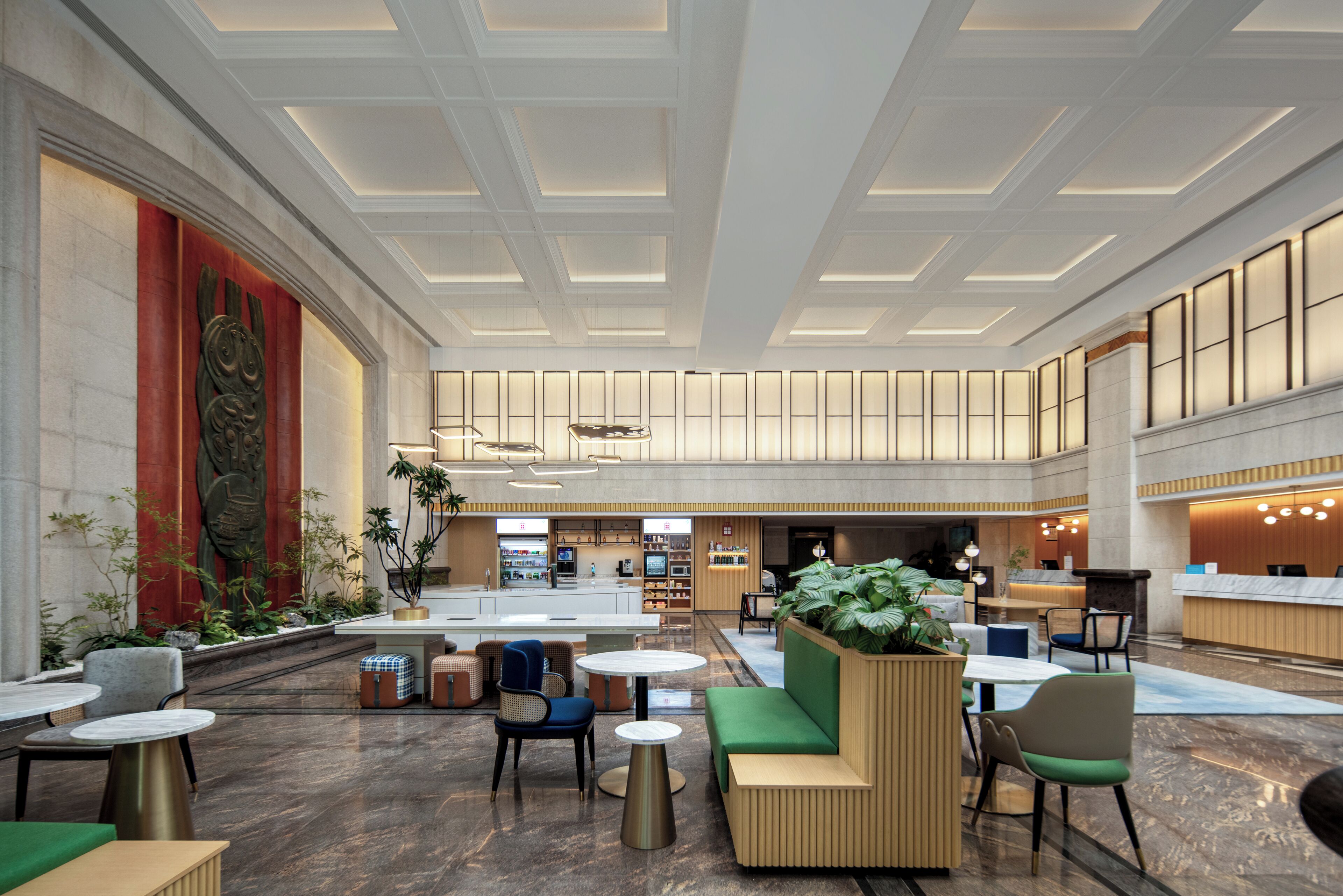 A spacious lobby with seating areas, a reception desk, and a large wall with a decorative sculpture.