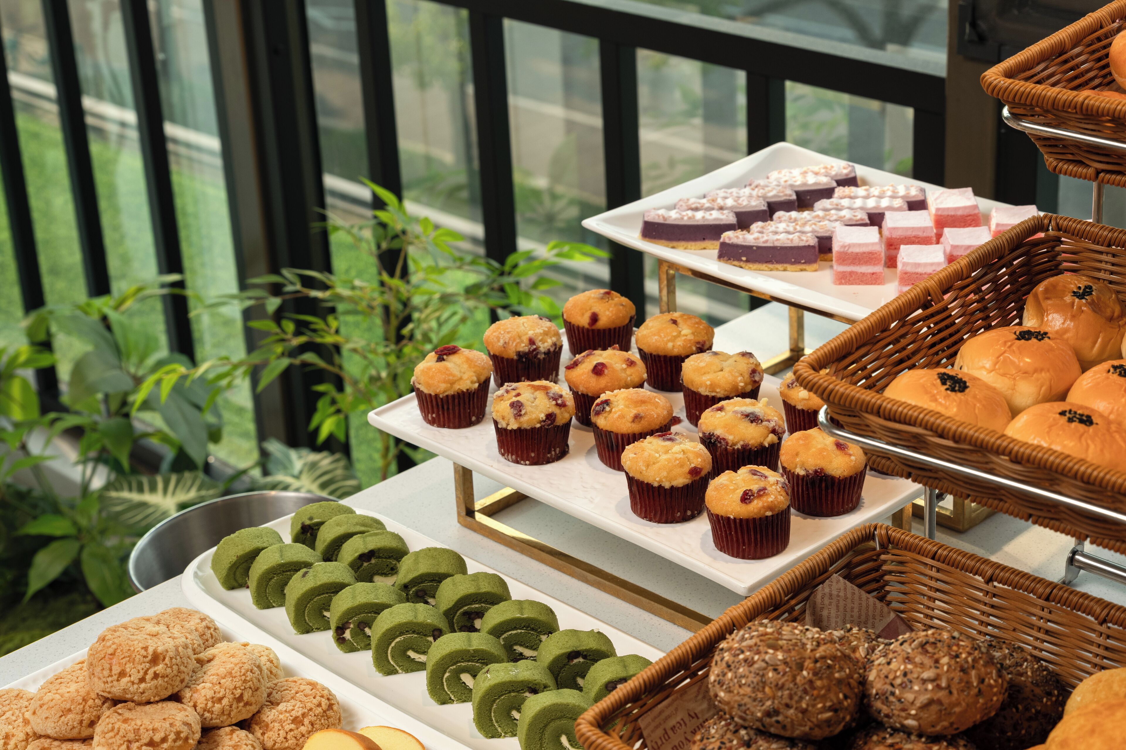 Un bufé con diversas opciones de repostería, incluyendo muffins y pasteles, dispuestas en múltiples fuentes y cestas.