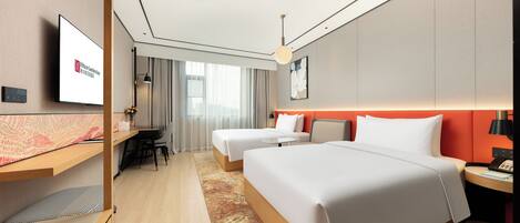 Habitación de hotel con dos camas, un escritorio, una televisión y vistas a la ciudad.