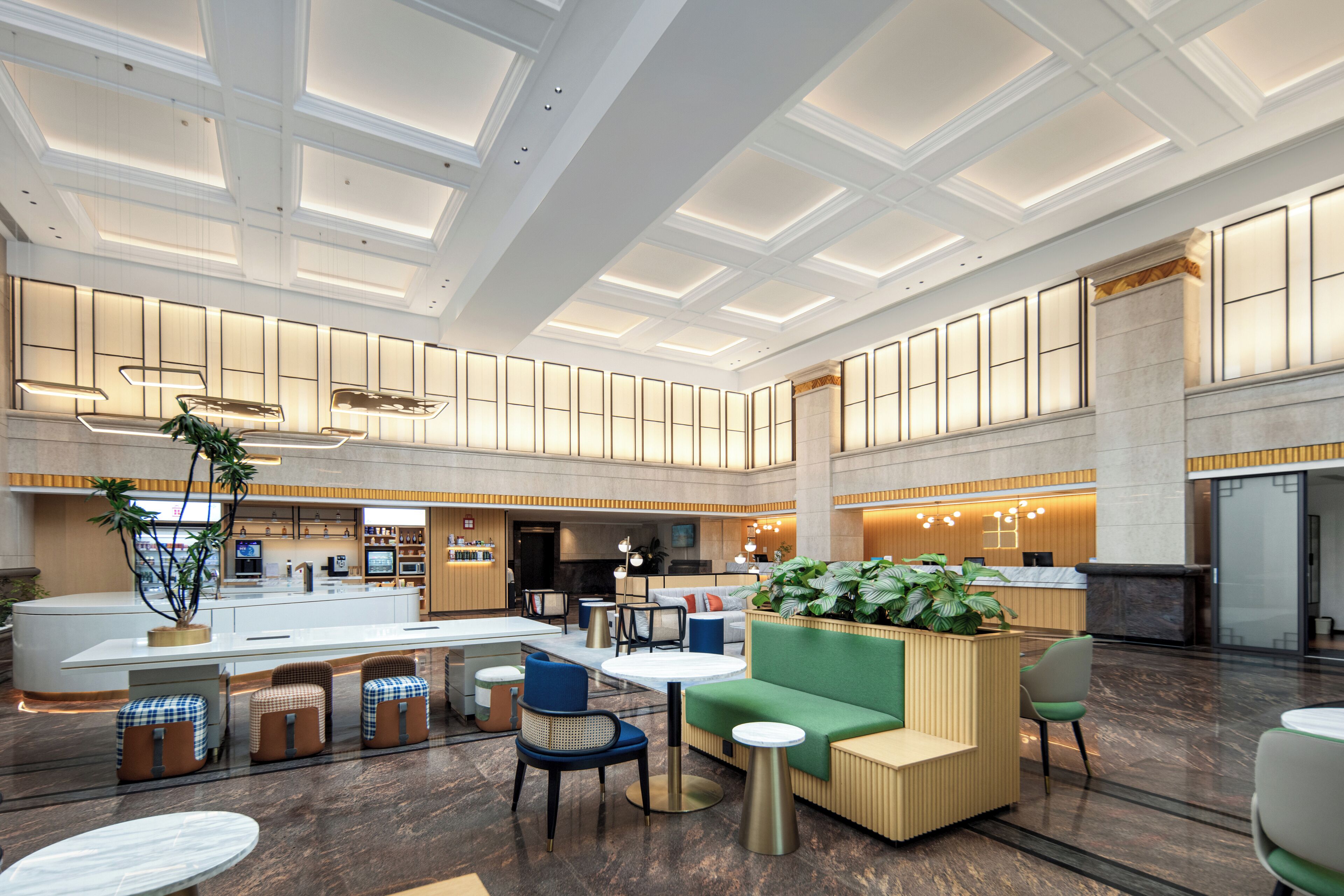 A spacious lobby with a central reception desk, seating areas, and a modern ceiling design.