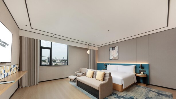 Une chambre d’hôtel moderne, dotée d’un grand lit, d’un canapé, d’un bureau et offrant une vue sur la ville.