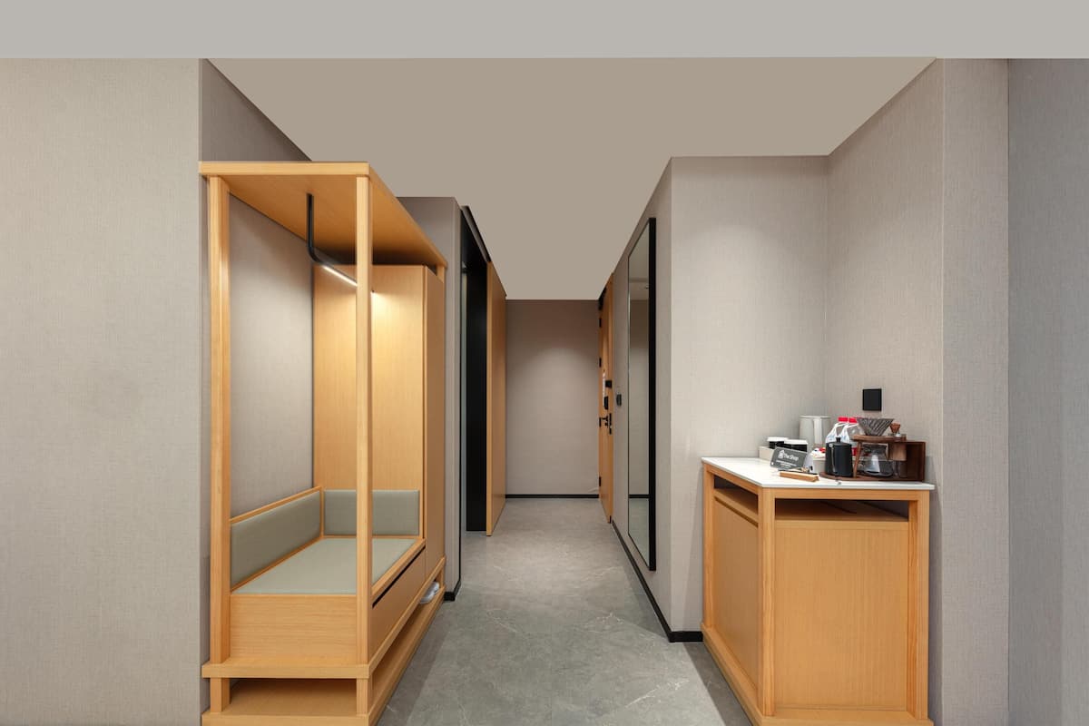 A narrow hallway with a wooden bench on the left and a small table with items on the right.
