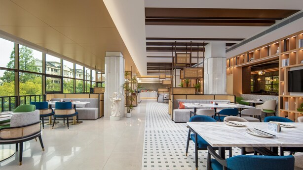 A modern restaurant with high ceilings, large windows, and a central dining area with tables and chairs. - Hilton Garden Inn Shanghai Jiading (Shanghai)