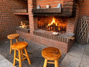 A brick fireplace with a fire, two wooden stools, and a basket of eggs. - Cozy & Central Oasis close to beach (Ratekau)