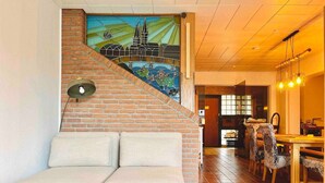 Ein Wohnzimmer mit einer Couch, einem Essbereich mit Stühlen, einer Treppe und einem Wandgemälde.