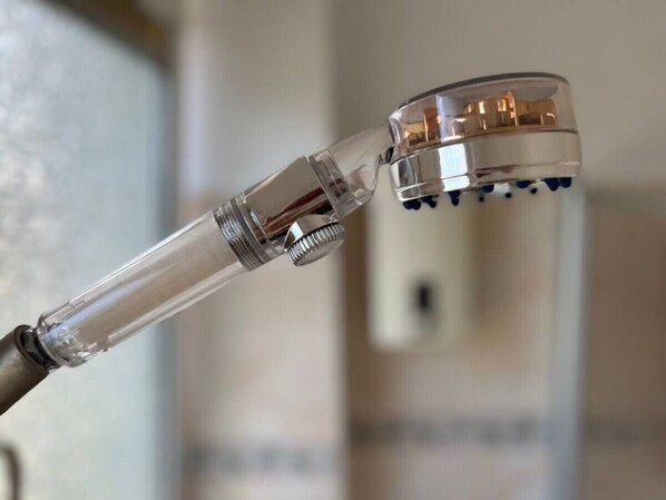 A showerhead with a transparent body and a metallic base.
