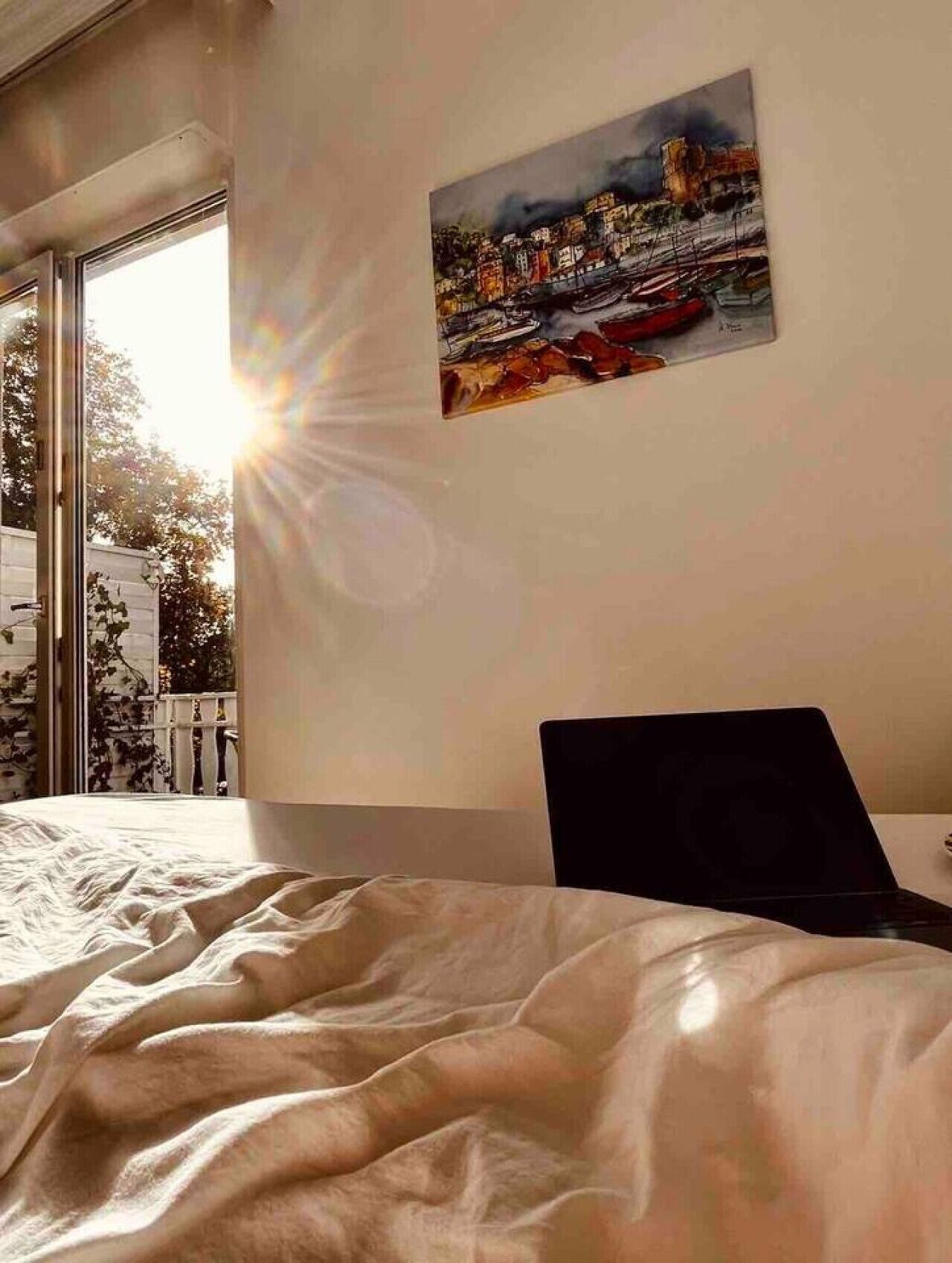 Ein Schlafzimmer mit einem Bett, einem Laptop auf einem Tisch und einem Bild an der Wand.