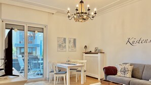 A living room with a dining area, a sofa, a chandelier, and a television.