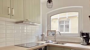 A kitchen with a window, a stove, an oven, and a coffee maker.