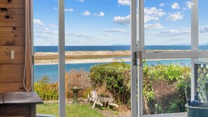 Udsigt fra et solarium med en glasdør, over en strand og havet.