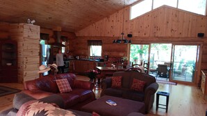 A log cabin interior with a living room, kitchen, and a balcony.