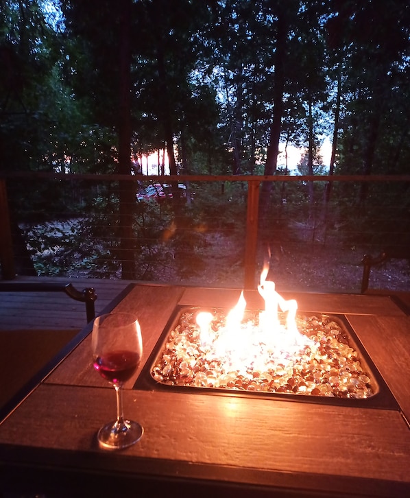 Una mesa con una copa de vino tinto y una chimenea.