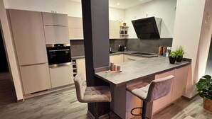 A modern kitchen with a central island, bar stools, and a built-in oven. - Erfurt Lakes vacation apartment - at the gates of the Thuringian state capital  (Nöda)