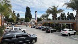 Un estacionamiento de hotel con varios coches, palmeras y un edificio con un letrero que dice "AMBER HOTEL".