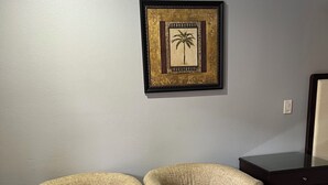 Una habitación con dos sillones y un reposapiés rojo sobre piso de madera.
