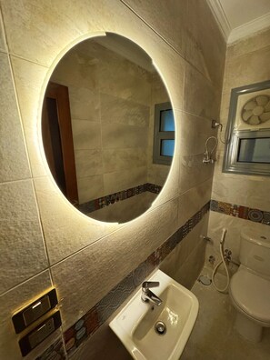 A bathroom with a round mirror, a sink, and a toilet.