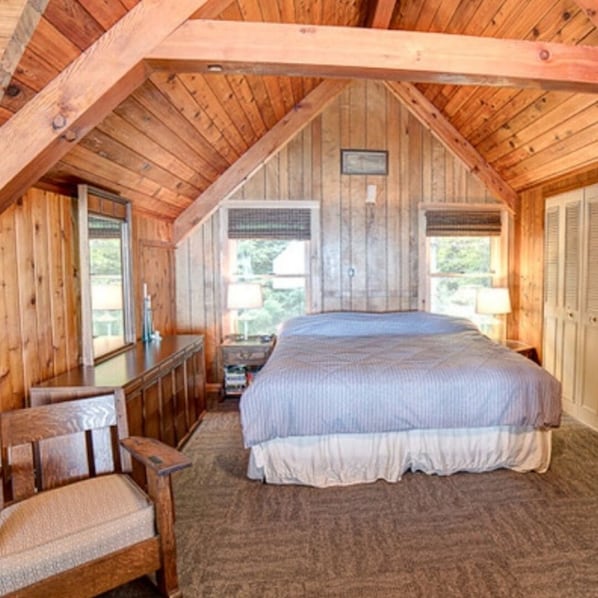 A bedroom with a wooden ceiling, a bed with a white and blue bedspread, a wooden nightstand, a chair, and a dresser. - Beaver Island - Cleveland's Big Chill (Beaver Island)