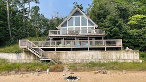 A two-story wooden cabin with a balcony, surrounded by trees. - Beaver Island - Cleveland's Big Chill  (Beaver Island)