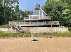 A two-story wooden cabin with a balcony, surrounded by trees.