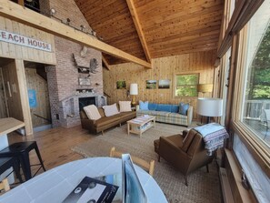 A cozy cabin interior with a fireplace, wooden walls, a sofa, and a dining area. - Beaver Island - Cleveland's Big Chill  (Beaver Island)