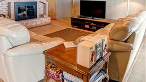 A living room with a brick fireplace, a television, and leather sofas. - Beaver Island - Cleveland's Big Chill  (Beaver Island)