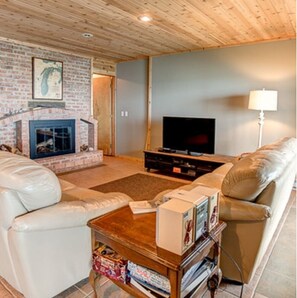 A living room with a brick fireplace, a television, and leather sofas.