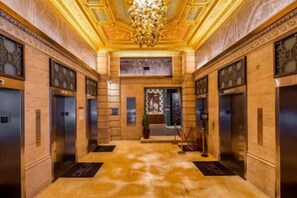 Experience the grandeur of our lobby, featuring an ornate chandelier, intricate patterns on the walls, and a patterned floor.
