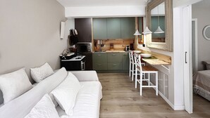 Un espace de vie compact comprenant un coin cuisine, un coin repas et un lit.