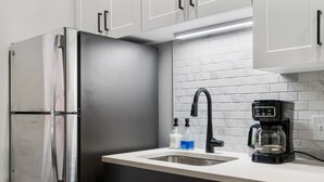 A modern kitchen with a stainless steel refrigerator, a black faucet, and a coffee maker on the countertop. - 2BR Near Fountain Sq.+ Carew Tower Deck | Downtown (Cincinnati)