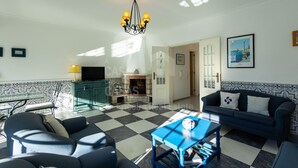 A living room with a checkered floor, a blue sofa, a blue table, and a chandelier.