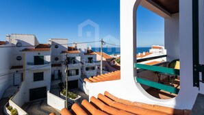 A white building with a balcony overlooking a coastal area.