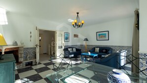 A living room with a checkered floor, a glass coffee table, a blue sofa, and a chandelier.