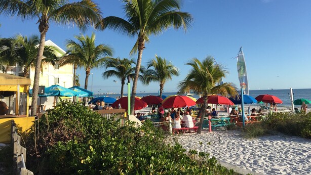 A beach with palm trees, umbrellas, and people. - Florida Vibes - A Fort Myers Gem- 2 Bedroom Condo.

 (Fort Myers)
