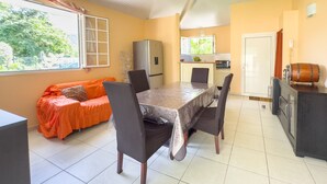 Un comedor con una mesa y sillas, un sofá, un refrigerador y una cocina con microondas.