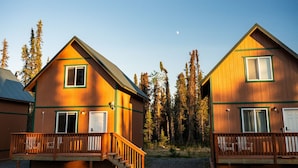 Two cabins with wooden exteriors, a balcony, and a clear view of the surrounding forest. - Kenai Fishing Cabin | Kitchen + Fire Pit (Kenai)