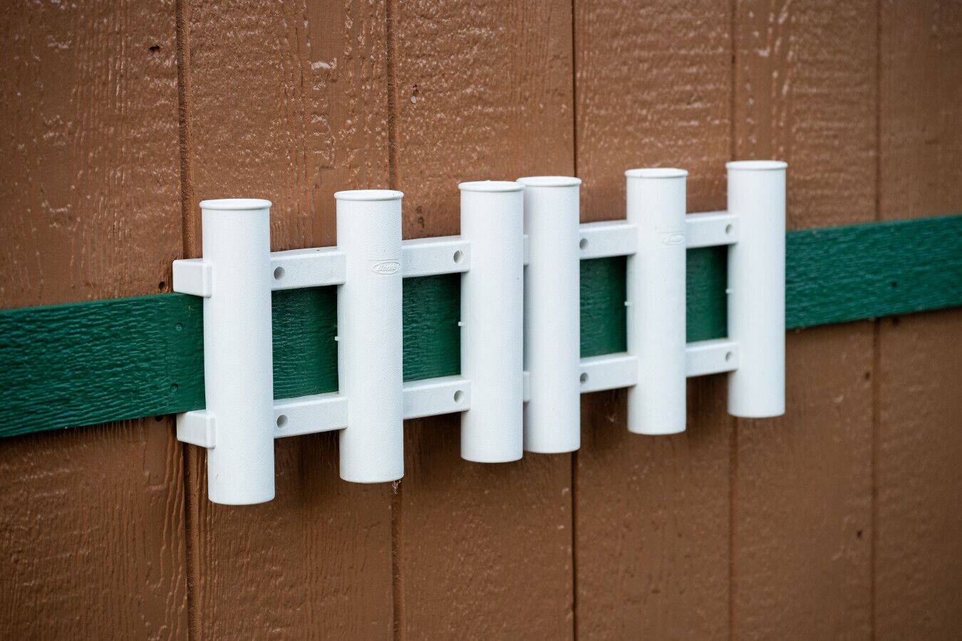 A white fence with evenly spaced vertical posts and a green horizontal bar.