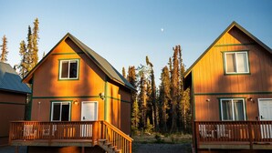 Two wooden cabins with balconies, set in a forested area. - Kenai Fishing Cabin | Walk-In Freezer & Grill (Kenai)