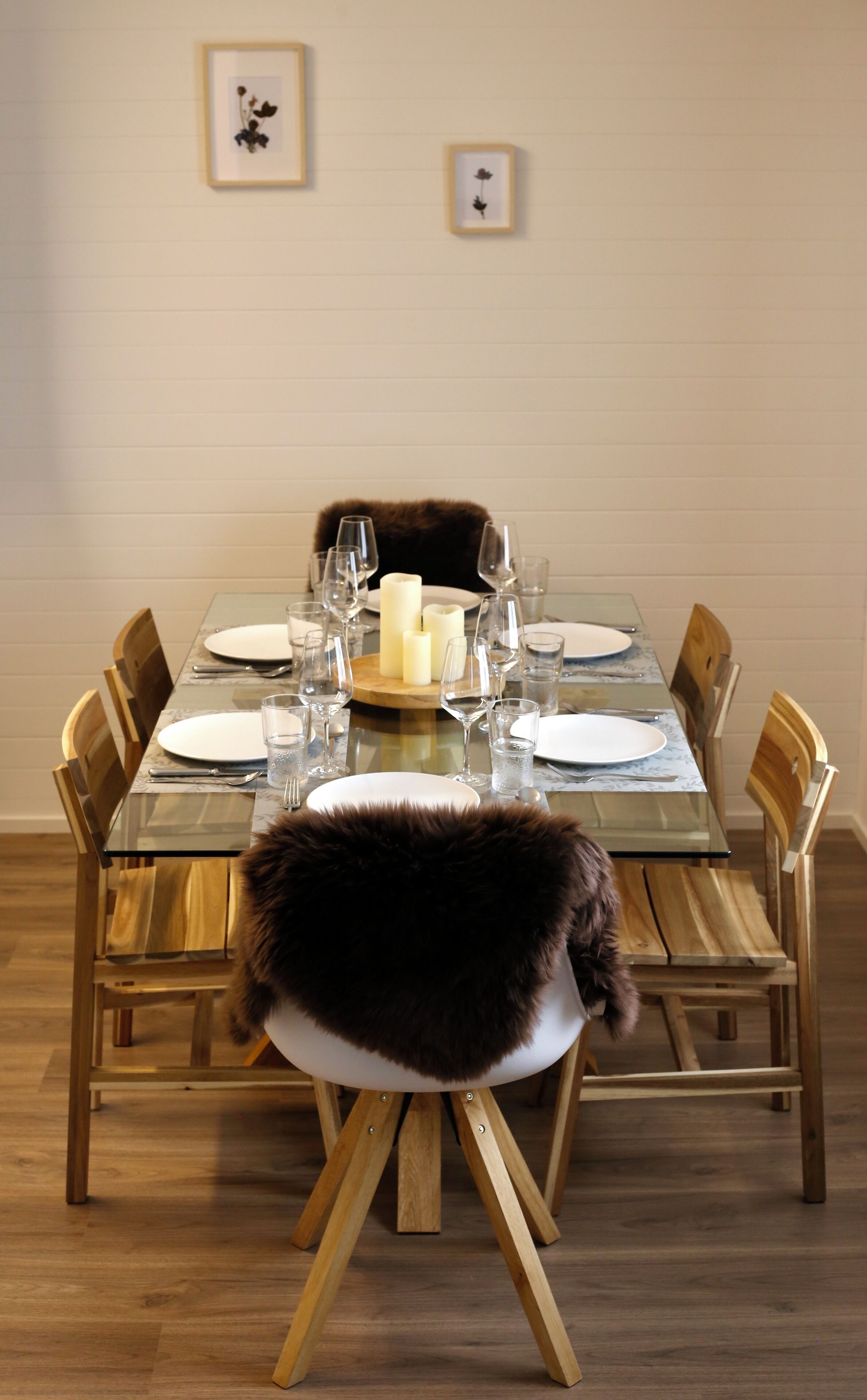 A dining table set with plates, glasses, and candles.