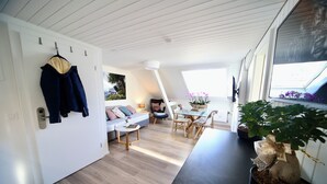 A modern interior with a dining area, a sofa, a table, and a potted plant. - ALP APARTMENTS with self check-in (Engelberg)