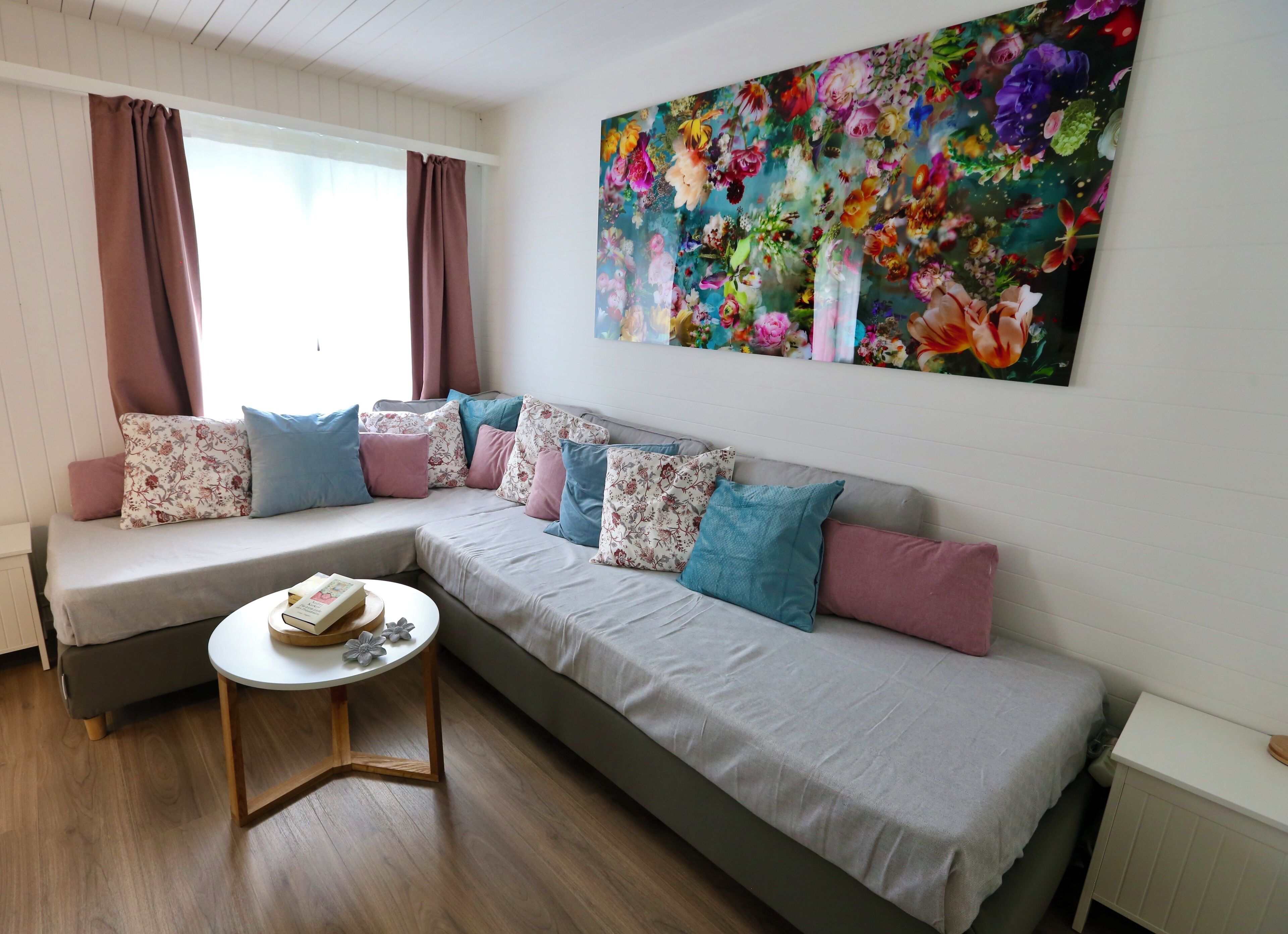 Una sala de estar moderna con un sofá modular, una mesa redonda de centro y una gran obra de arte floral en la pared.