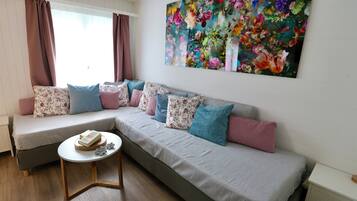Una sala de estar moderna con un sofá modular, una mesa redonda de centro y una gran obra de arte floral en la pared.
