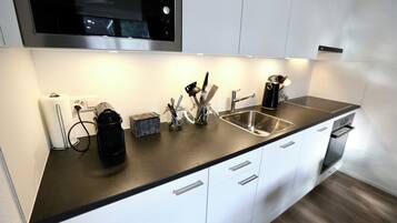 A modern kitchen with a stainless steel sink, white cabinets, and a black countertop.
