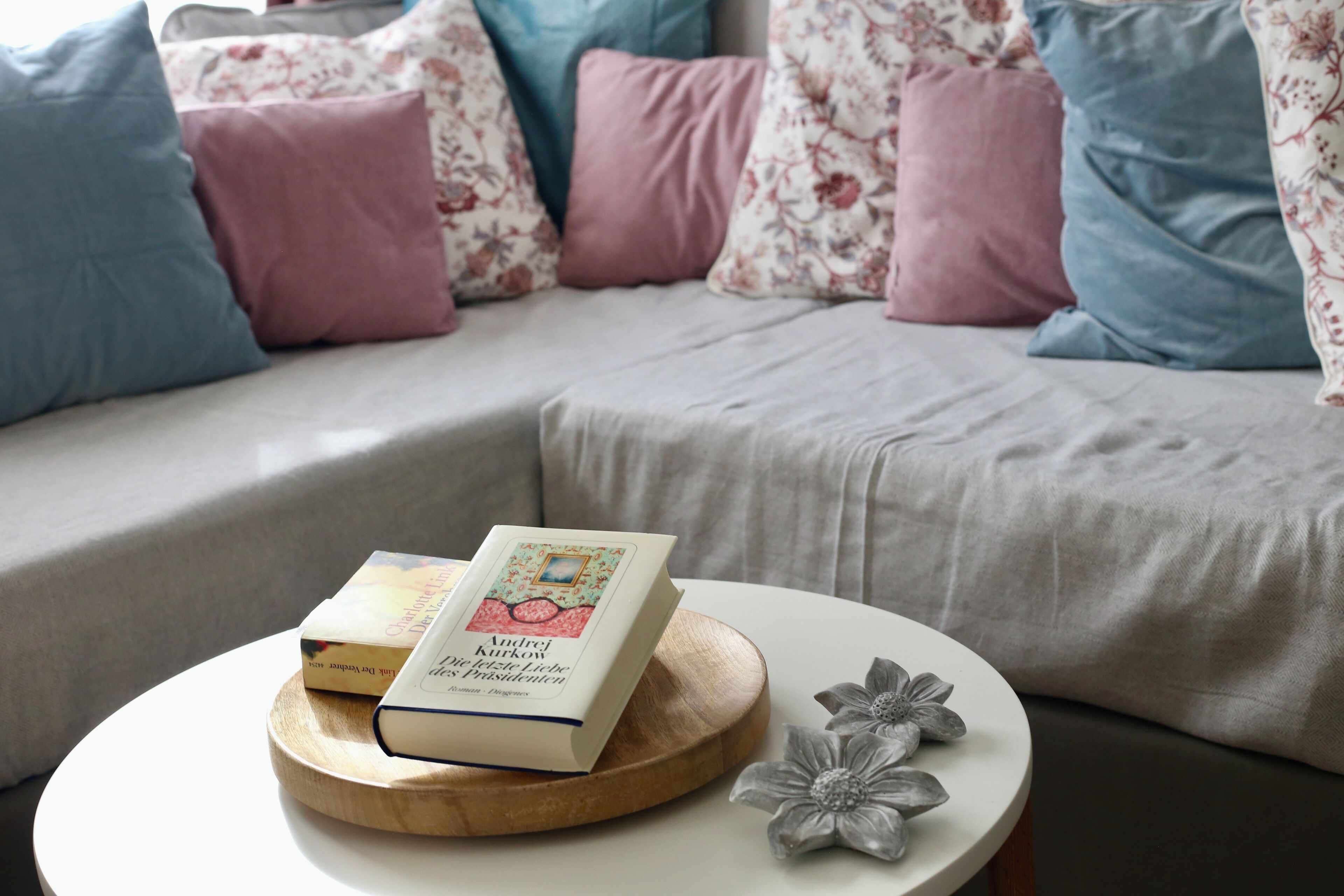 A book titled "Andrej Kurkow Die Festliche Liebe" on a wooden coaster on a round white table.