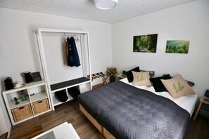 A bedroom with a bed, a wardrobe, a desk, and two paintings on the wall.