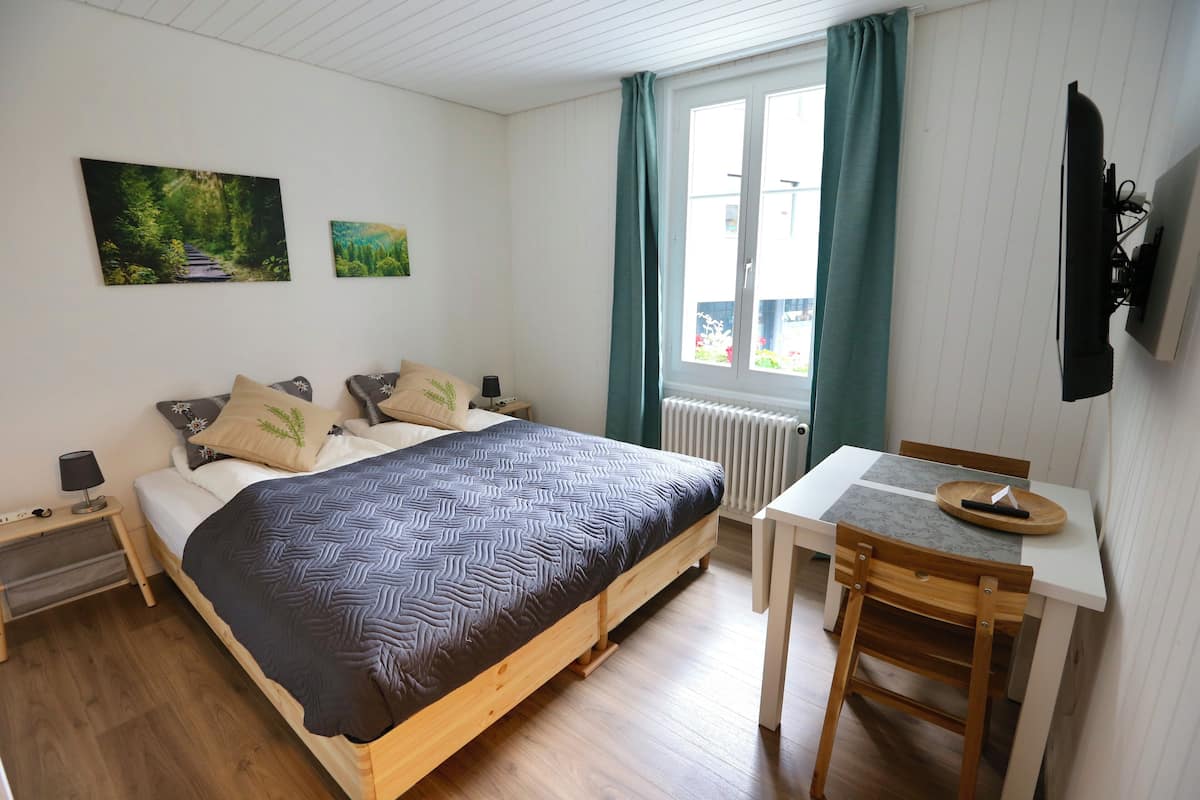 A bedroom with a bed, bedside table, and a desk with a chair.
