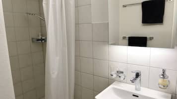 Ein Badezimmer mit Dusche, Waschbecken, Spiegel und Handtuchhalter.