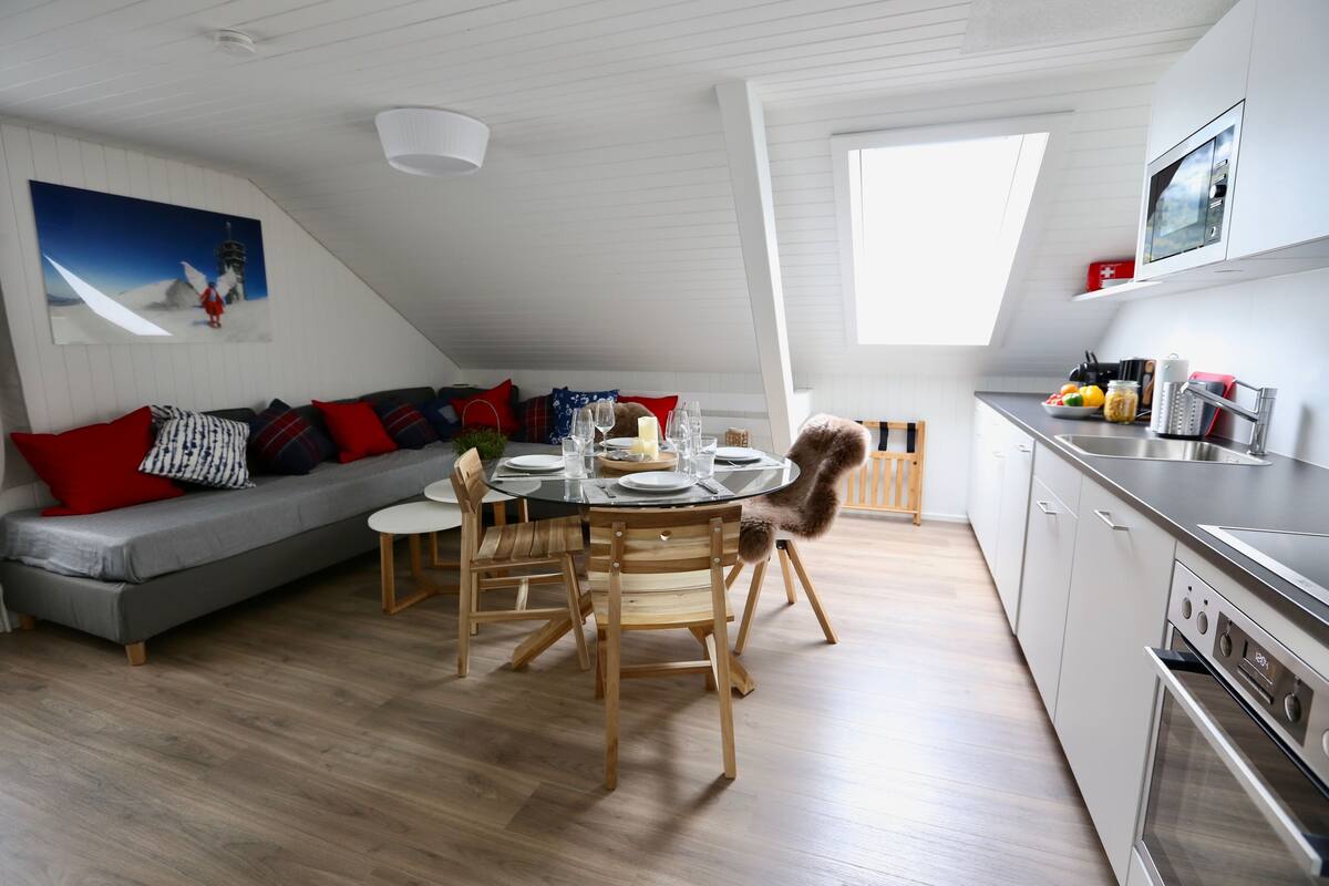 A modern loft apartment with a dining area, kitchen, and living space.