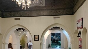 A lobby with a chandelier, arched doorways, a reception desk, and a vase on a table. - Mazar Resort & Spa By Kemet (Sharm El Sheikh)