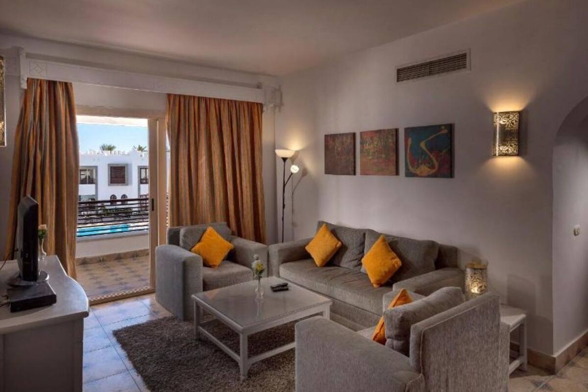 A modern living room with a grey sofa set, a coffee table, and a TV on a stand. There are two floor lamps and artwork on the wall.
