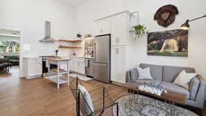 Eine moderne Küche mit weißen Schränken, einem Edelstahlkühlschrank und einem Essbereich mit Holztisch und Stühlen.